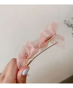 Dettaglio del fermaglio per capelli con fiocco in organza rosa e clip in metallo oro