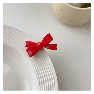 Close-up of a glossy red bow hair clip featuring a minimalist vintage palace style design