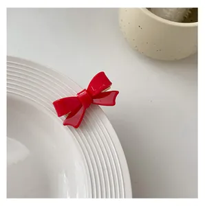 Detailed view of a bright red acrylic bow hair clip attached to a white ceramic plate
