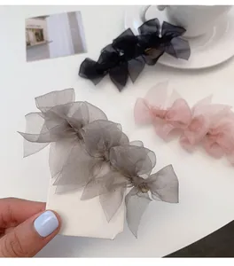 Dettaglio di fermagli per capelli a fiocco in rete grigio, nero e rosa con clip d'oro