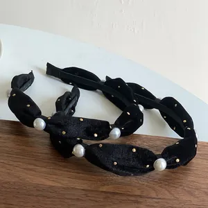 Retro black velvet headbands with golden dots and white baroque pearls on wooden surface
