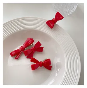 Close-up of vibrant red bow hair clips on white ceramic tray with glossy resin finish