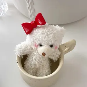 Cute white plush bear with big red bow placed in a ceramic cup for hair accessory decor