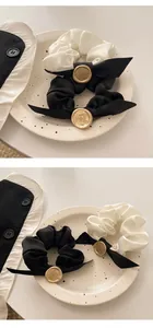 Macro detail of French vintage satin scrunchies with bow and gold crest seal accent