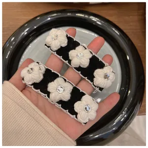 Pair of black velvet hair clips with white knit camellia flowers and sparkling rhinestones