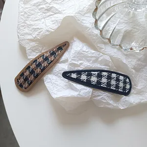 Detail of vintage houndstooth fabric hair clips in brown and black on a white background