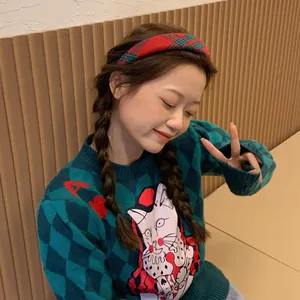 Close-up of red and green plaid headband paired with green knit rabbit pattern sweater