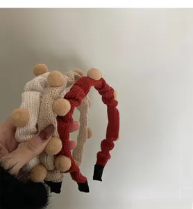 Detail von gestrickten Faltenstirnbändern mit Bommeln in Beige, Khaki und Weinrot