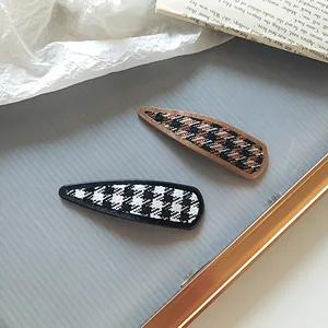Close-up of hounds-tooth pattern hair clips on a vintage decorative display plate