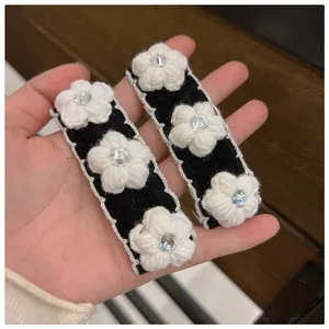 Detailed close-up of knit camellia flower hair clips with sparkling rhinestone centers