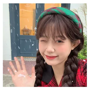 Close-up of a wide plaid headband in red and green festive colors worn by a model
