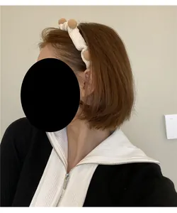 Detail eines beigen Strickstirnbands mit Bommeln am Model für Weihnachtsfrisuren