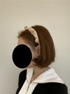Detail eines beigen Strickstirnbandes mit Plüschpompons für Damen in der Nahaufnahme