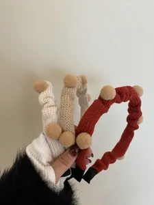Nahaufnahme gestrickter Stirnbänder mit Plüschbällen in Creme, Khaki und Dunkelrot