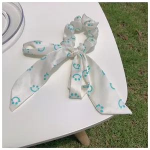 Détail du chouchou nœud crème avec de longs rubans et des motifs de visages souriants