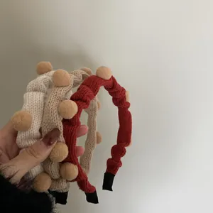 Detail der gestrickten Winterstirnbänder mit braunen Bommeln in Rot, Beige und Khaki