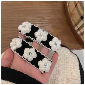 Detail of handmade knit camellia hair clips with velvet base and sparkling rhinestones