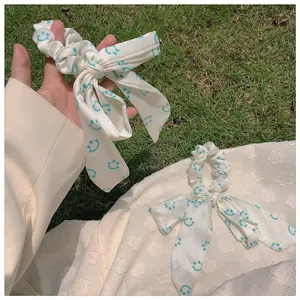 Détails de chouchous à nœuds blancs avec motifs smiley verts et longs rubans fluides