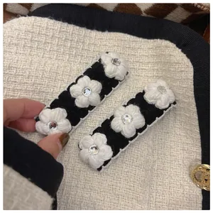 Set of two black knitted camellia hair clips with white crochet flowers and crystals
