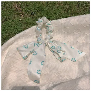 Détail d'un chouchou en satin blanc avec longs rubans et motifs de smileys bleus