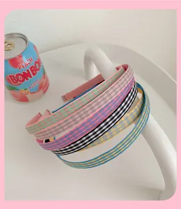 Détail de serre-têtes doux à carreaux et rayures colorés sur un support blanc