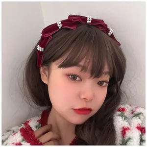 Close-up of wine red velvet headband with ruffled texture and white pearl embellishments