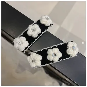 Detailed close-up of velvet hair clips with knit camellia flowers and rhinestone accents