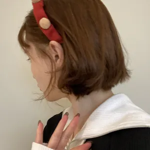 Roter Weihnachts-Strickhaarreif mit Pompons, getragen von einem Model in Seitenansicht