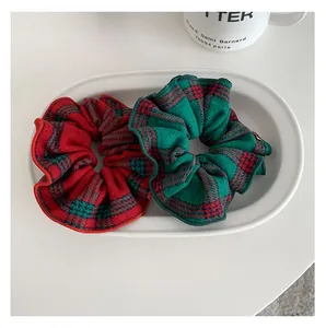 Close-up of red and green plaid scrunchies in a ceramic tray with festive vibes