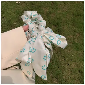 Vue détaillée du chouchou en satin blanc avec motifs smileys bleus et nœud élégant