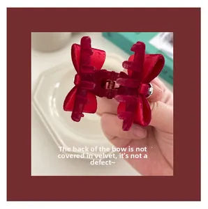 Detailed view of a red velvet bow hair claw clip with flocking finish and metal spring