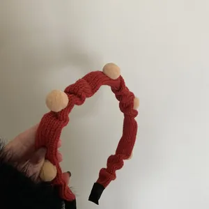 Roter gestrickter Weihnachts-Haarreif mit beigen Pompons und gerippter Wolltextur