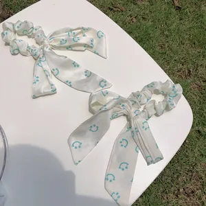 Détail de chouchous crème avec de longs rubans et des motifs de smileys turquoise
