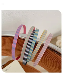 Détail de six serre-têtes fins en tissu à carreaux colorés sur un support vintage