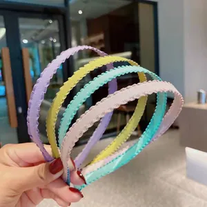 Close-up of four pleated fabric headbands in pastel candy colors with scalloped edges