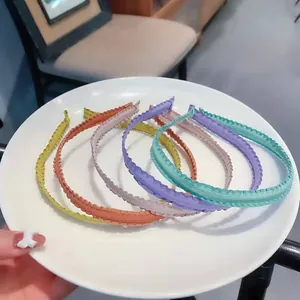 Close-up of six colorful pleated fabric headbands displayed on a white ceramic plate