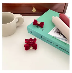 Detail of vintage red velvet bow hair clips with rhinestones on a mint book