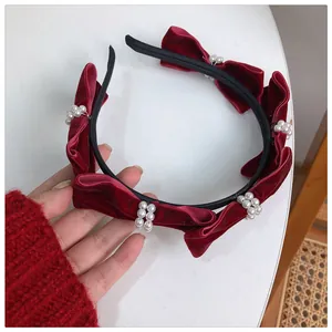 Detailed shot of burgundy velvet headband with bow ties and faux pearl embellishments