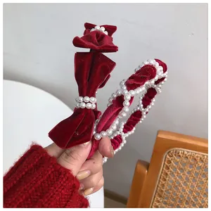 Detail of red velvet headband with pearls and bow on a warm rustic background