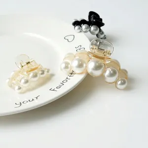 Elegant pearl hair clips in black and amber resin on a ceramic plate, assorted sizes
