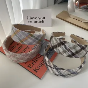 Set of four autumn plaid sponge headbands in various colors on a minimalist desk setup