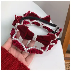 Detailed close-up of red velvet headband set with elegant pearls and bowknot decoration