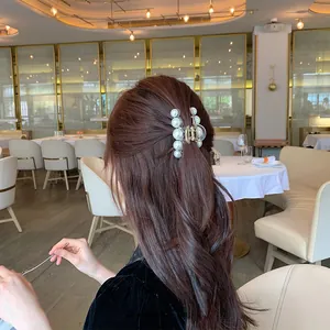 Detail of elegant gold pearl hair claw clip worn on long wavy hair in a French style