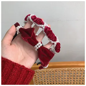 Detail of red velvet Christmas headband with pearls and bow held by a model