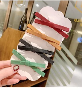 Close-up of four ribbed fabric bow hair clips in red, yellow, black and green colors