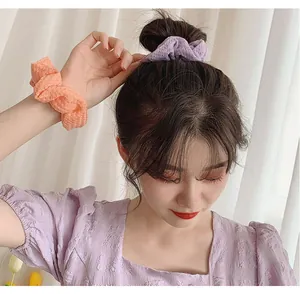 Detail of soft knit scrunchie in pastel orange and purple worn on a girl's wrist