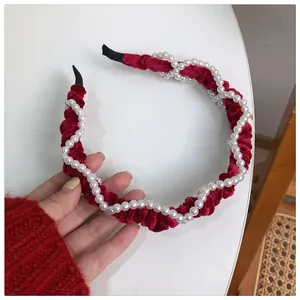 Detail view of red velvet headband with elegant white pearls and soft pleated texture