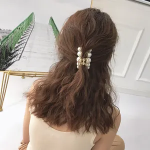Elegant medium pearl hair claw clip in gold finish shown on wavy brown hair