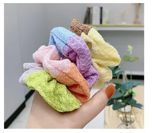 Detail shot of multi-color waffle knit scrunchies in vibrant colors held in hand