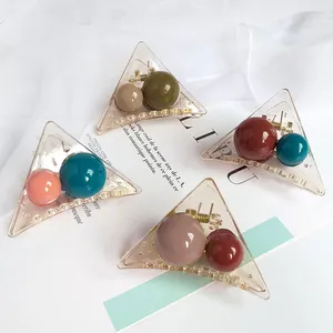 Set of four transparent triangular acrylic hair claws with colorful beads on fabric